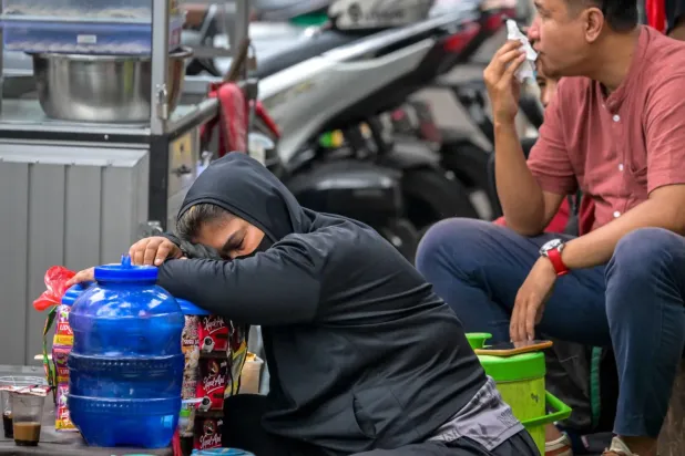 Cakarta'da müşterilerini beklerken tezgâhında uyuyan bir kahve satıcısı (AFP)