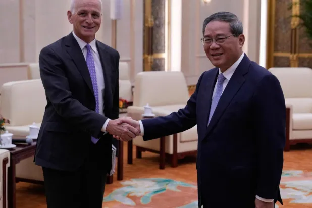 النائب الديمقراطي وعضو لجنة القوات المسلحة بمجلس النواب الأميركي آدم سميث (يسار) يصافح رئيس مجلس الدولة الصيني لي تشيانغ خلال لقائهما في قاعة الشعب الكبرى ببكين اليوم (أ.ف.ب)