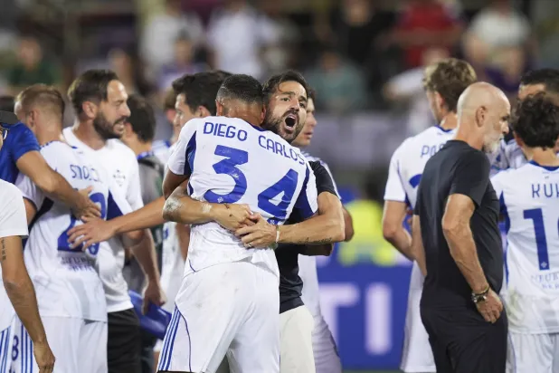 سيسك فابريغاس مدرب كومو يحتضن لاعبه دييغو كارلوس احتفالاً بالفوز العصيب على فيورنتينا (أ.ب)