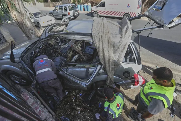 عناصر في الدفاع المدني أمام السيارة التي استُهدفت بغارة إسرائيلية في بنت جبيل مساء الأحد وذهب ضحيتها 5 قتلى بينهم 3 أطفال (أ.ب)