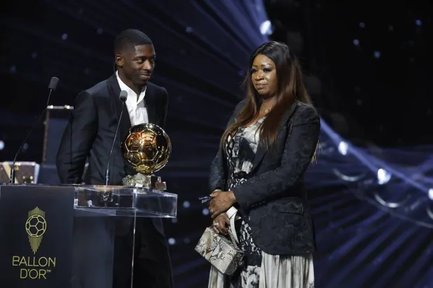 المهاجم الفرنسي عثمان ديمبيلي يحتفل بالكرة الذهبية إلى جوار والدته (إ.ب.أ)