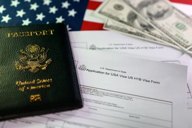 A US flag, a passport, mock US dollars and US H-1B Visa application forms are seen in this illustration taken, September 22, 2025. REUTERS/Dado Ruvic/Illustration
