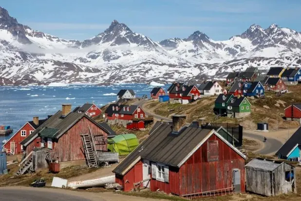 ترتفع الجبال المغطاة بالثلوج فوق الميناء في تاسيلاك بغرينلاند (رويترز)