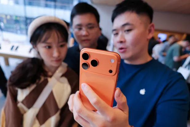موظف يعرض هاتف «آيفون» الجديد للمتسوقين في بكين (رويترز)