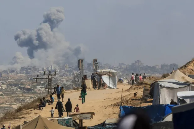 Smoke rises from an Israeli strike, as displaced Palestinians, fleeing northern Gaza due to an Israeli military operation, move southward after Israeli forces ordered residents of Gaza City to evacuate to the south, in the central Gaza Strip September 24, 2025. (Reuters)