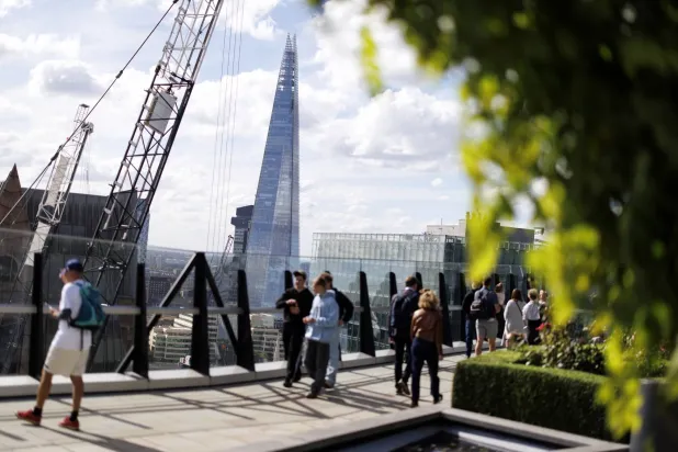 أشخاص يمرون بجوار مبنى «شارد» وحي المال في مدينة لندن (إ.ب.أ)