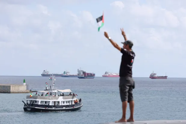 (FILES) An activist waves the Palestinian flag as a boat carrying Swedish climate activist Greta Thunberg and activists, part of a civilian flotilla aiming at breaking the Israeli blockade of the Gaza Strip, leaves the port of Barcelona on August 31, 2025. (Photo by Lluis GENE / AFP)
