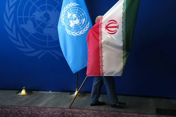 رجل يسحب العلم الإيراني من القاعة عقب لقاء الرئيس مسعود بزشكيان بالأمين العام للأمم المتحدة أنطونيو غوتيريش خلال أعمال الجمعية العامة للأمم المتحدة في نيويورك (أ.ف.ب)