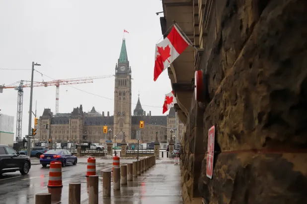 أعلام تتدلّى على مبنى مكتب رئيس الوزراء في أوتاوا (رويترز)
