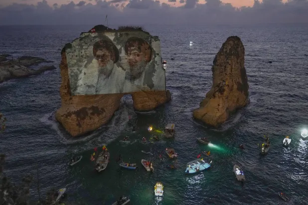 Portraits of former Hezbollah leaders Hassan Nasrallah, right, and Hashem Safieddine, are projected onto the landmark Raouche sea rock during an event commemorating the anniversary of their assassination, in Beirut, Lebanon, Thursday, Sept. 25, 2025. (AP Photo/Hussein Malla)