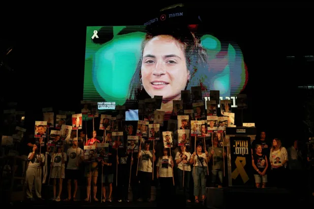 عرض صورة الرهينة إنبار هايمان التي قُتلت بغزة خلال مظاهرة في تل أبيب تطالب بإبرام صفقة للإفراج عن الرهائن في غزة (رويترز)