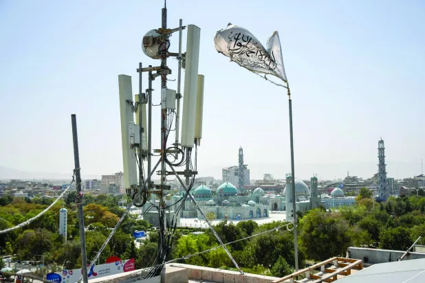 يرفرف عَلم «طالبان» بالقرب من معدات اتصالات مُثبّتة على سطح مبنى يوفر خدمة الإنترنت (أ.ف.ب)