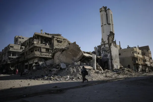 امرأة فلسطينية تمشي بجوار أبنية دُمرت جراء غارة جوية إسرائيلية في مدينة غزة يوم 30 سبتمبر 2025 (إ.ب.أ) 