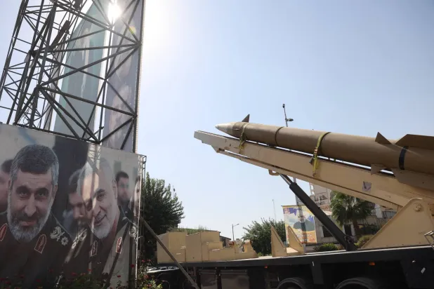 صاروخ باليستي إيراني يُعرض في شارع وسط طهران بجوار لافتة تحمل صورة المسؤول السابق للعمليات الخارجية في «الحرس الثوري» قاسم سليماني ومسؤول البرنامج الصاروخي أمير علي حاجي زاده الذي قُتل بضربة إسرائيلية يونيو الماضي (رويترز)