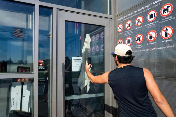أحد المارة في العاصمة الأميركية يلتقط صورة لإشارة تابعة لهيئة المتنزهات الوطنية توضح أن نصب واشنطن مغلق بسبب إغلاق الحكومة (غيتي)