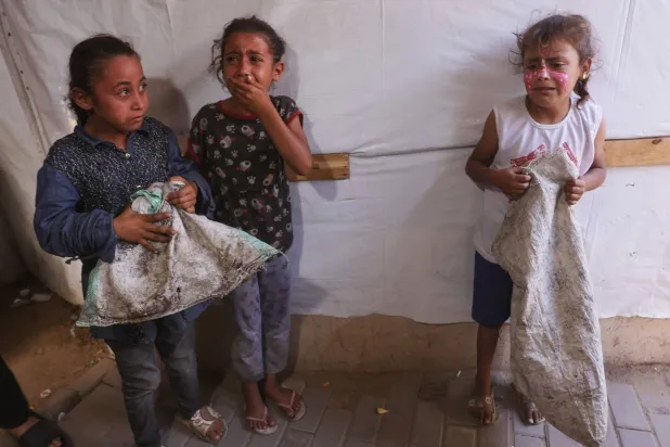 فتيات فلسطينيات يبكين بعد غارة إسرائيلية استهدفت خيمة يستخدمها نازحون داخل مستشفى في دير البلح وسط قطاع غزة أمس (أ.ف.ب)