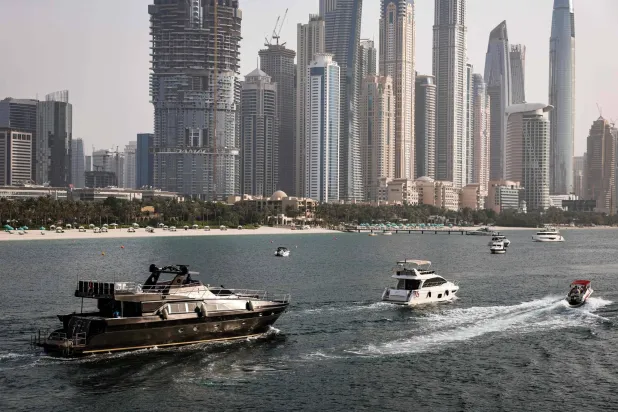 يبحر يخت وقوارب أخرى قرب أبراج مرسى دبي (أ.ف.ب)