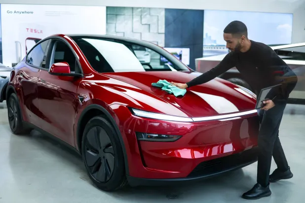 موظف ينظف سيارة «تسلا» في صالة عرض بمدينة نيويورك الأميركية (أ.ف.ب)
