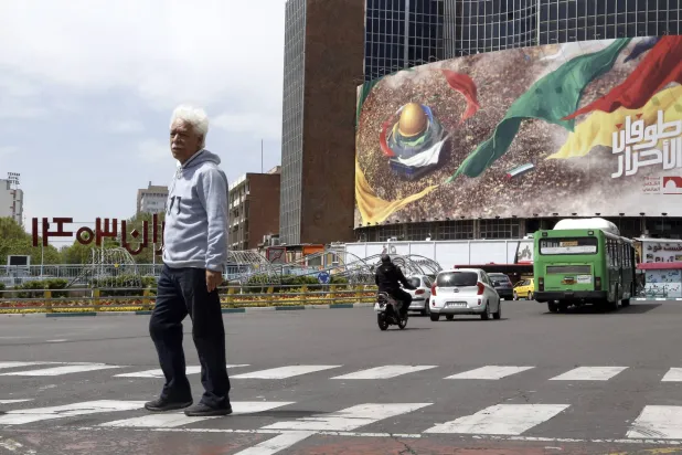 رجل إيراني يمشي أمام لوحة إعلانية مناهضة لإسرائيل في طهران (إ.ب.أ)