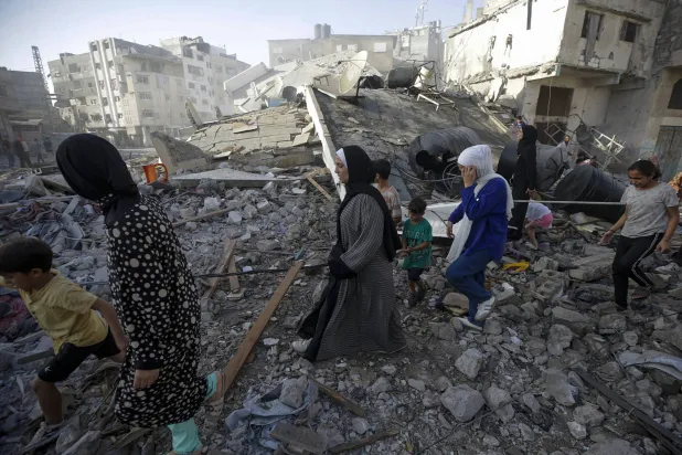 عائلة فلسطينية تتفقد أنقاض منزلها المدمر في مدينة غزة (إ.ب.أ) 