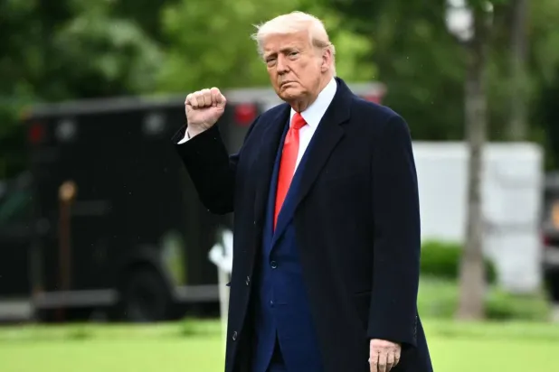 ترمب يرفع قبضته أثناء توجهه نحو طائرة الهليكوبتر الرسمية مارين وان على حديقة البيت الأبيض (أ.ف.ب)