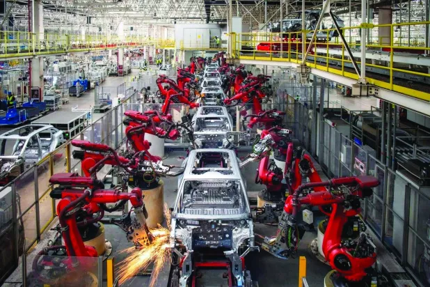 جانب من تجميع الأذرع الآلية على خط إنتاج سيارات كهربائية بمصنع في جينهوا الصينية (رويترز)