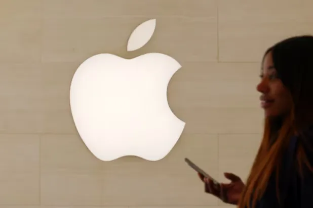 A woman walks past an Apple logo inside an Apple store in Paris, France, April 23, 2025. REUTERS/Abdul Saboor 