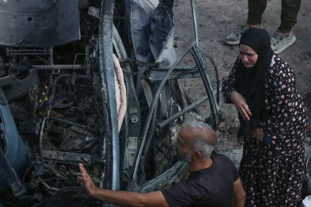 سيدة ورجل أمام السيارة التي استُهدفت بغارة إسرائيلية في منطقة زبدين في الجنوب وأدت إلى مقتل مصاب بتفجيرات «البيجر» وزوجته (أ.ف.ب)
