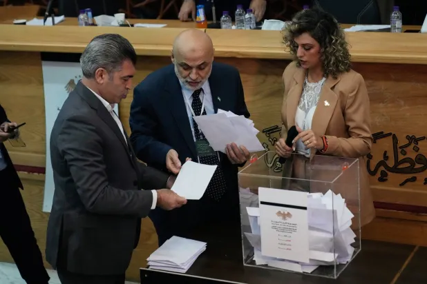 أعضاء الهيئة الانتخابية السورية والمرشحون يتابعون فرز الأصوات بعد وقت قصير من إغلاق مراكز الاقتراع في مبنى محافظ اللاذقية (أ.ب)