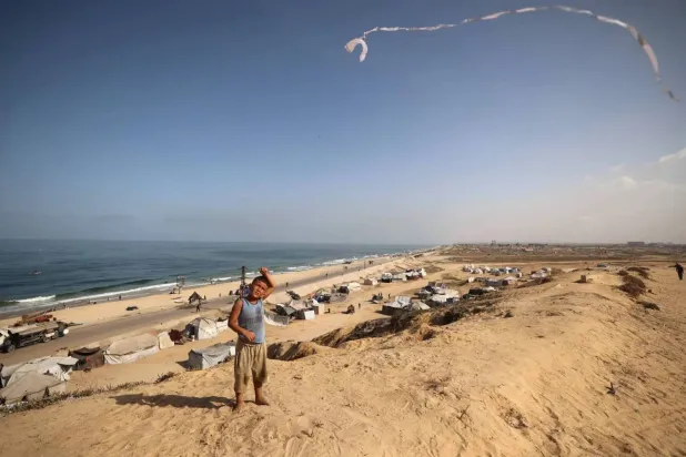 A Palestinian boy flies his kite near tents of displaced families in the Nuseirat camp, in the central Gaza Strip (AFP). 
