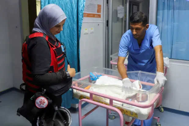 A medical worker prepares to evacuate a premature baby from Al Helo International Hospital to be transported to a hospital in southern Gaza for further medical care, amid an Israeli military operation, in Gaza City October 3, 2025. REUTERS/Ebrahim Hajjaj 
