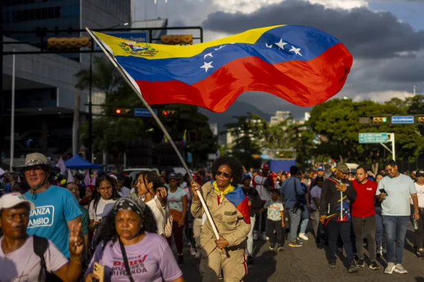 امرأة تلوح بعلم فنزويلي في مسيرة دعمًا للحكومة الفيدرالية في كاراكاس في مواجهة التهديد الذي يشكله الانتشار البحري الأميركي في البحر الكاريبي (إ.ب.أ)