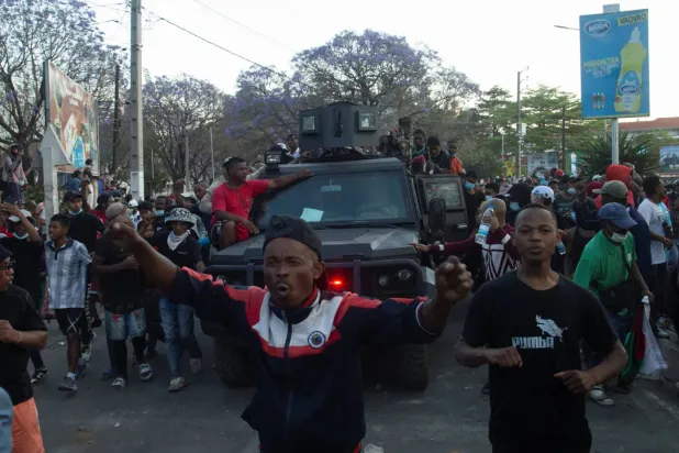 Madagaskar'ın başkenti Antananarivo'da gösteriler sırasında protestocular bir askeri aracın yanından geçiyor (Reuters)