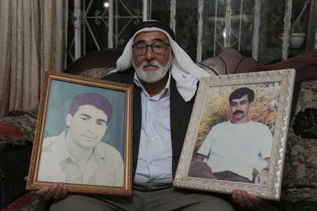 Yousef Shamasneh, 83, holds portraits of his two imprisoned sons, Abdel Jawad, right, and Mohammad, at his home in the West Bank village of Qatanna, west of Jerusalem, Friday, Oct. 10, 2025. (AP) 