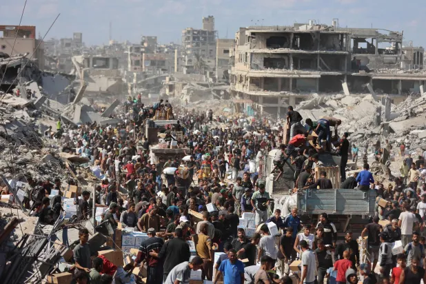 فلسطينيون يحتشدون حول شاحنات مساعدات بعد دخولها إلى قطاع غزة عبر معبر كرم أبو سالم في خان يونس أمس (أ.ف.ب)