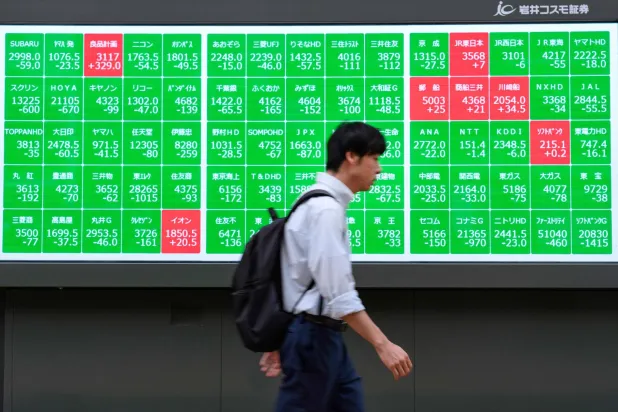 رجل يمر أمام لوحة إلكترونية تعرض حركة الأسهم في وسط العاصمة اليابانية طوكيو (أ.ف.ب)