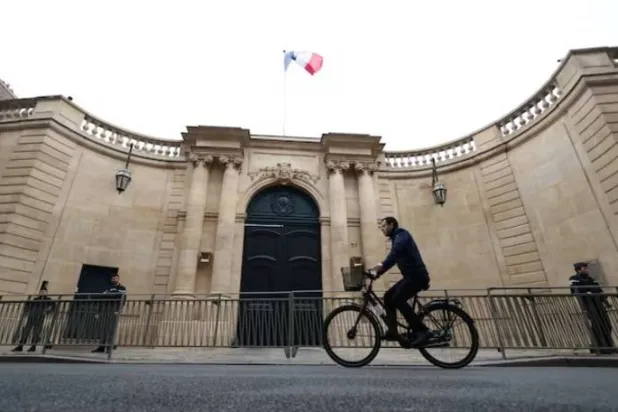 رجل يقود دراجته الهوائية أمام فندق «ماتينيون» في باريس (رويترز)