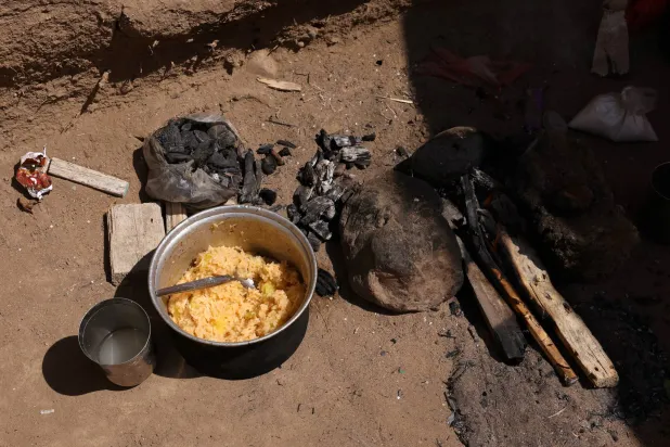 وجبة مطبوخة موضوعة على الأرض داخل ملجأ بمخيم للنازحين في عدن (رويترز)