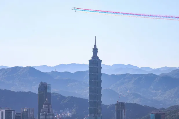 Three AT-3 advanced jet trainers release coloured trails as they fly in formation past the Taipei 101 building as part of rehearsals ahead of Taiwan's National Day, also refered to as Double Ten Day, in Taipei on October 2, 2025. (Photo by I-Hwa Cheng / AFP)