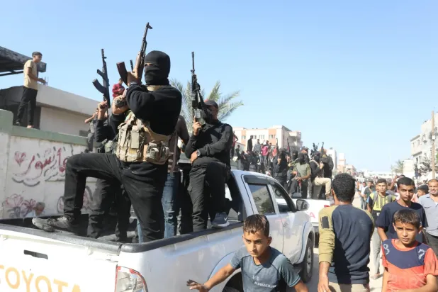 Hamas savaşçıları, 13 Ekim 2025'te Han Yunus'ta İsrail tarafından serbest bırakılan Filistinli mahkûmları taşıyan otobüslere eşlik ediyor. (DPA)