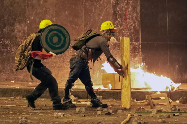 متظاهرون في بيرو يرتدون خوذات ودروعاً ويشتبكون مع شرطة مكافحة الشغب (أ.ف.ب)