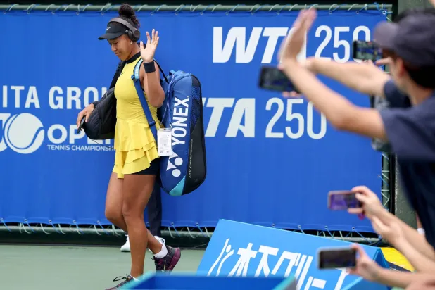 Japan's Naomi Osaka waves to fans as she arrives to play against Netherlands' Suzan Lamens during their women's singles match at the Japan Open tennis tournament in Osaka on October 15, 2025. (Photo by PAUL MILLER / AFP)