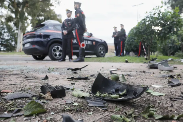 Parts of a car are seen on the ground as Carabinieri military police stand outside the home of investigative journalist Sigfrido Ranucci after an explosive device detonated under the car, in Pomezia, Italy, Friday, Oct. 17, 2025. (Cecilia Fabiano/LaPresse via AP)