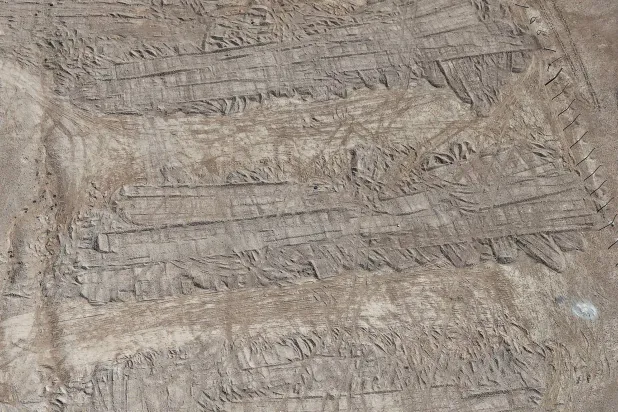 A drone view of imprints, made by bulldozer tracks, on the soil covering a burial trench of a mass grave in the eastern Syrian desert near the town of Dhumair, February 27, 2025. REUTERS/Khalil Ashawi
