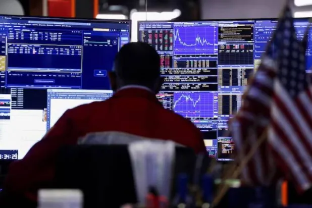 متداول يراقب شاشة الأسهم في قاعة بورصة نيويورك (رويترز)
