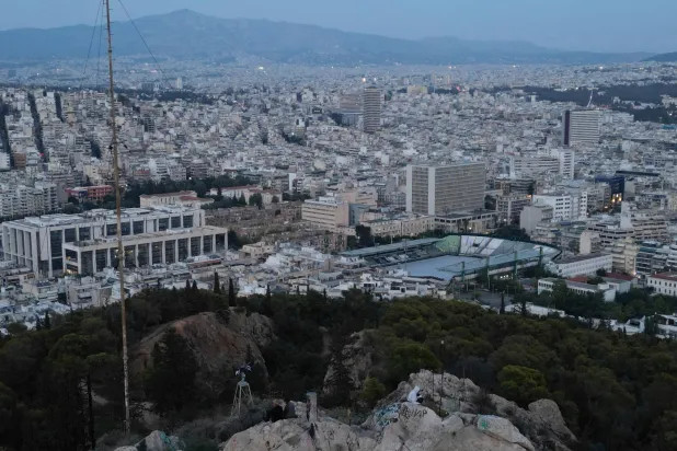 Youths sit on a rock on Lycabettus hill overlooking Athens, Greece, Wednesday, Oct. 15, 2025. (AP Photo/Thanassis Stavrakis)
