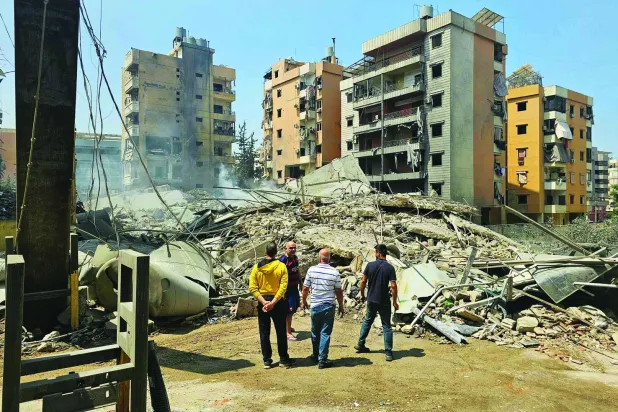 لبنانيون يقفون قبالة مبانٍ دمَّرتها غارات إسرائيلية استهدفت الضاحية الجنوبية لبيروت في يونيو 2025 (أرشيفية - أ.ف.ب)