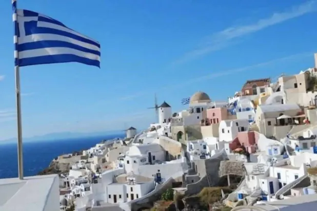 علم اليونان يرفرف أعلى مدينة ساحلية قرب أثينا (رويترز)