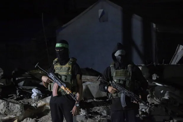 مقاتلون من «كتائب القسام» يحرسون مركبات للصليب الأحمر وصلت لنقل جثث رهائن إسرائيليين بمدينة غزة الأربعاء الماضي (إ. ب.أ)