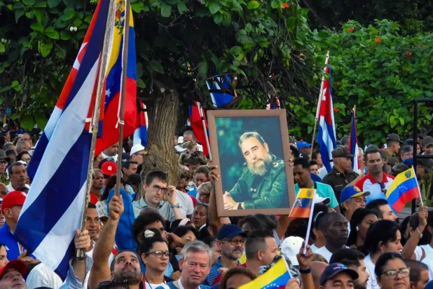 Havana'da 17 Ekim'de ABD'nin askeri güçlerini artırmasının ardından ülkeye destek olmak için Fidel Castro'nun fotoğrafları ve Venezuela bayrakları taşıyan protestocular (AFP)